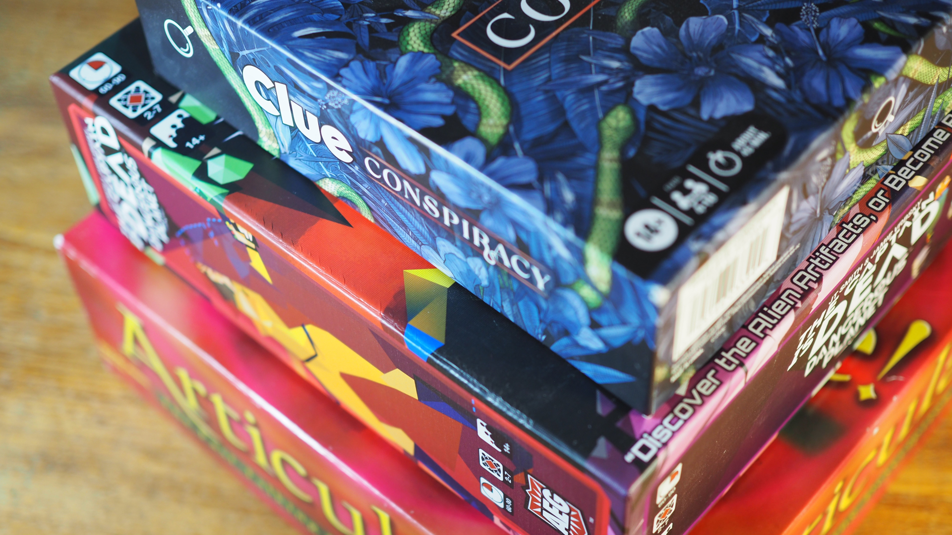 Clue Conspiracy, The Captain is Dead: Dangerous Planet et Articulate! empilés sur une table en bois