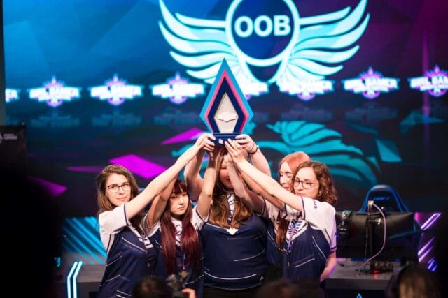Équipe féminine levant un trophée sur scène.