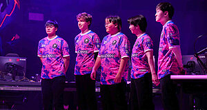 Équipe e-sport debout sur scène en uniforme violet.