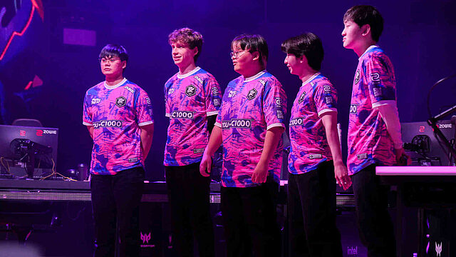 Équipe e-sport debout sur scène en uniforme violet.