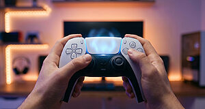 Manette de jeu devant un écran lumineux.