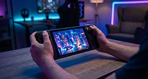 Close-up of hands holding a Steam Deck, displaying a vibrant futuristic city game scene with blue/purple/orange lights in a dim room.