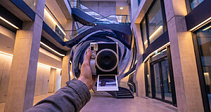 Main tenant un appareil photo dans un hall moderne.