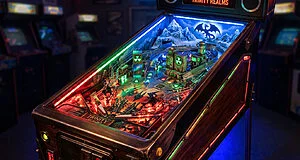 Machine de flipper Bethesda 'Trinity Realms' aux thèmes Skyrim et Fallout. Plateau illuminé avec dragon, montagnes et symboles nucléaires.