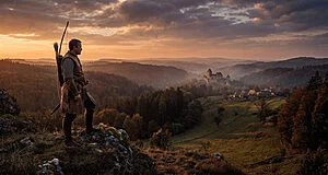 Guerrier médiéval avec arc sur une crête rocheuse. Il regarde un château, un village et des collines boisées au coucher du soleil.