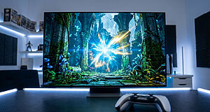 Écran affichant Crimson Desert sur PS5 avec une explosion lumineuse. Une manette DualSense blanche et noire est posée sur un bureau éclairé.