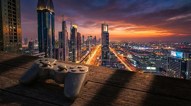 Manette de jeu devant une ville grandiose au crépuscule Manette de jeu sur bois, face à une métropole moderne au coucher de soleil, avec gratte-ciel scintillants et traînées de lumières.