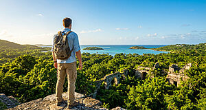 Homme avec sac à dos sur une falaise, regardant la mer turquoise, les îles, la jungle luxuriante et des ruines antiques.
