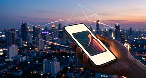Une main tient un smartphone affichant un graphique financier à la hausse devant une ville connectée au crépuscule.