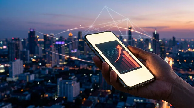 Une main tient un smartphone affichant un graphique financier à la hausse devant une ville connectée au crépuscule.