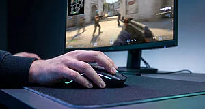 Main d'un joueur posée sur une souris gaming devant un écran affichant une partie intense de Counter-Strike 2.