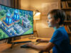 Un jeune garçon joue à Minecraft sur un grand écran incurvé, affichant une centrale nucléaire cubique détaillée.