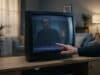 Netflix : arrêt sur les anciens appareils et solutions Une main pointe un écran de télévision cathodique affichant de la neige statique et le reflet d'un homme.