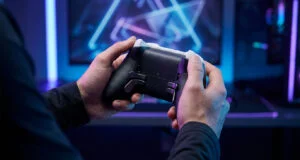 Gros plan sur les mains d'un joueur tenant une manette PS5 pro personnalisée devant un écran de jeu rétroéclairé.