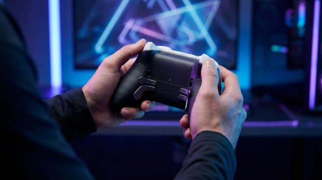 Gros plan sur les mains d'un joueur tenant une manette PS5 pro personnalisée devant un écran de jeu rétroéclairé.
