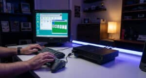 Mains jouant au Solitaire Windows 95 sur un écran CRT relié à une console PlayStation 2 posée sur un bureau.