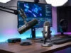 Setup de streaming professionnel avec deux micros sur un bureau en bois devant un écran affichant un logiciel.
