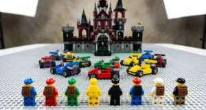 Huit figurines LEGO et des karts miniatures alignés sur une plaque de base devant un grand château en briques LEGO.