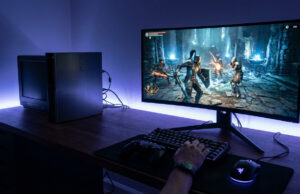 Émulateur RPCS3 et jeux PS3 : ta parade à la fin du Store Une personne joue à un jeu vidéo sur PC avec un clavier, une souris et une console PS3 posée sur le bureau éclairé.