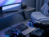 Un joueur portant des gants lumineux utilise un clavier et une souris dans un setup gaming moderne avec éclairage néon.