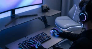 Un joueur portant des gants lumineux utilise un clavier et une souris dans un setup gaming moderne avec éclairage néon.