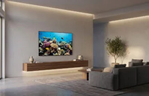 HDMI sans fil 4K : la solution pour libérer votre salon Salon épuré avec téléviseur mural affichant un récif corallien, sans aucun câble visible sous l'appareil.