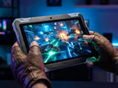 Meilleures tablettes gaming 2026 : quel modèle pour jouer ? Une personne porte des gants en cuir et joue à un jeu vidéo futuriste sur une tablette robuste dans un décor gaming.