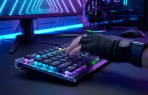 Une main gantée utilisant un clavier gaming mécanique avec éclairage RGB dans un setup PC futuriste.