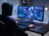 Warzone : quel VPN choisir pour éviter les lobbies tryhard ? Un joueur en sweat à capuche devant un écran de jeu avec des effets holographiques numériques.