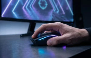 Gros plan sur une main de gamer utilisant une souris rétroéclairée devant un écran de jeu avec un viseur.