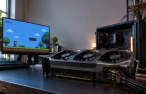 Une RTX 5090 fondue en jouant au pixel art, garantie refusée Carte graphique RTX 5090 gravement brûlée au niveau du connecteur d'alimentation posée sur un bureau devant un écran.
