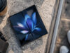 Un smartphone pliant Samsung Galaxy Z Fold ouvert posé sur une surface en pierre avec un café à côté.
