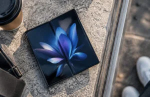 Un smartphone pliant Samsung Galaxy Z Fold ouvert posé sur une surface en pierre avec un café à côté.