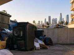 Un joueur trouve un PC gaming performant à Los Angeles Un boîtier de PC gaming noir posé au sol près de poubelles, avec les gratte-ciels de Los Angeles en arrière-plan.