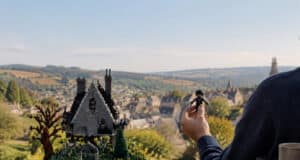 Un fan tient une figurine LEGO d'Edward aux mains d’argent devant une maquette détaillée de son château iconique.