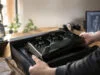 Un artiste 3D découvre une RTX 5090 signée par Jensen Huang Un artiste 3D déballe une carte graphique RTX 5090 noire avec une signature dorée de Jensen Huang sur son bureau.