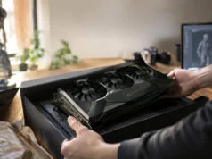 Un artiste 3D découvre une RTX 5090 signée par Jensen Huang Un artiste 3D déballe une carte graphique RTX 5090 noire avec une signature dorée de Jensen Huang sur son bureau.