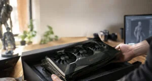 Un artiste 3D déballe une carte graphique RTX 5090 noire avec une signature dorée de Jensen Huang sur son bureau.