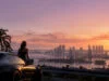 Comprendre l’histoire de gta 6 et ses enjeux scénaristiques Une personne assise sur une voiture de sport, observant le coucher de soleil sur une ville côtière inspirée de Miami.