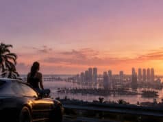 Comprendre l’histoire de gta 6 et ses enjeux scénaristiques Une personne assise sur une voiture de sport, observant le coucher de soleil sur une ville côtière inspirée de Miami.