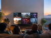 Groupe d'amis jouant à des jeux vidéo sur une télévision grand écran dans un salon confortable.
