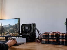 Un PC de bureau Ryzen démarre sous Linux avec 192 piles AA Un PC Ryzen sous Linux alimenté par une rangée de 192 piles AA connectées par des câbles sur un bureau en bois.