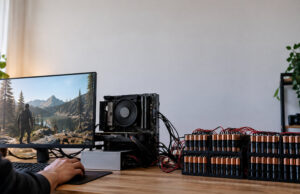 Un PC de bureau Ryzen démarre sous Linux avec 192 piles AA Un PC Ryzen sous Linux alimenté par une rangée de 192 piles AA connectées par des câbles sur un bureau en bois.