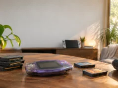 Trois nouveaux Game Boy Advance sur Nintendo Switch Online Console Game Boy Advance violette posée sur une table en bois entourée de plusieurs cartouches de jeux.