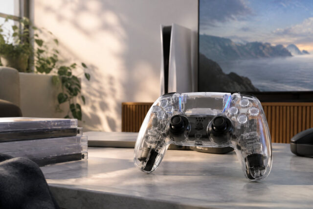 Une manette DualSense au style rétro transparent Une manette DualSense transparente posée sur une table devant une console PS5, évoquant le design des années 90.