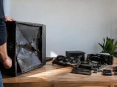 Un PC gamer acheté 20 € aux enchères, une vraie aubaine Un homme inspecte un boîtier PC gamer gravement endommagé avec des composants démontés sur une table en bois.