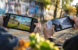 Deux mains tenant des consoles portables affichant des paysages de jeux vidéo différents sur un fond urbain.