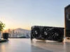 Prix de la RTX 5090 : ce qu’il faut savoir sur son tarif Carte graphique haute performance posée sur un bureau devant une fenêtre avec vue panoramique sur Marseille au coucher.