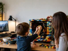 Un garçon de 5 ans crée un PC LEGO pour la Fête des Pères Un jeune garçon et une femme assemblent des briques LEGO autour d'un boîtier d'ordinateur sur un bureau en bois.