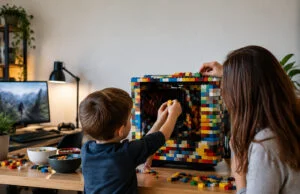 Un garçon de 5 ans crée un PC LEGO pour la Fête des Pères Un jeune garçon et une femme assemblent des briques LEGO autour d'un boîtier d'ordinateur sur un bureau en bois.